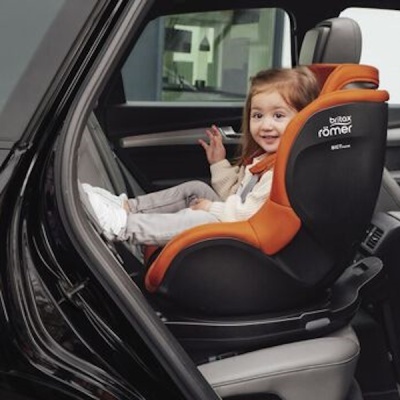 Cadeira auto Britax Römer laranja e preta com criança sentada no banco traseiro de carro