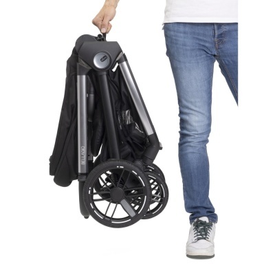 Carrinho de bebé dobrável preto com rodas grandes e estrutura prateada, sendo segurado por uma mão.