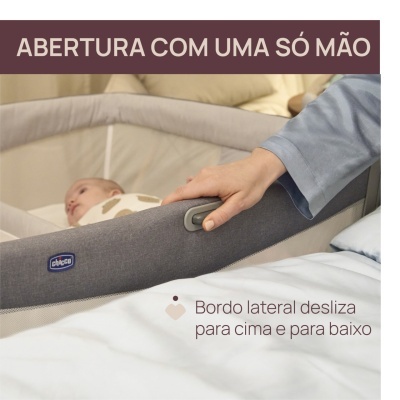 Berço de bebé cinzento com borda lateral ajustável e mão a usar botão