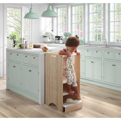 Criança numa cozinha moderna a usar uma escada de madeira para alcançar o tampo da bancada.