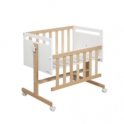 Berço de bebé em madeira clara e branca com laterais de ripas e rodas.