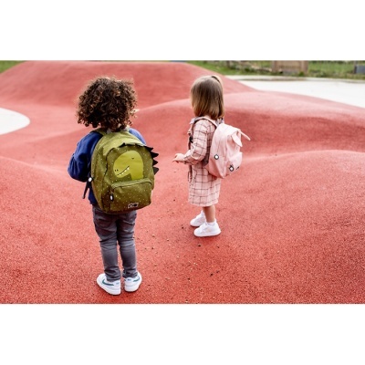 Crianças com mochilas de dinossauro verde e rosa em chão vermelho ao ar livre