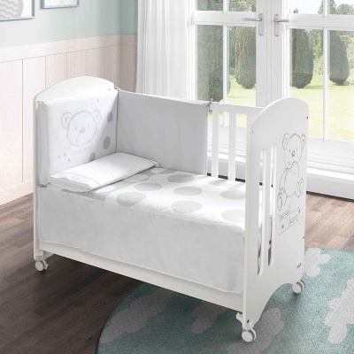 Berço branco para bebé com protetor lateral cinzento decorado com urso e roupa de cama com padrão de círculos cinzentos