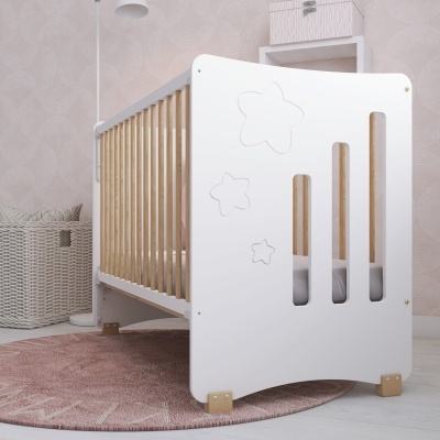 Berço infantil branco com recortes de estrelas e ripas de madeira, tapete rosa e papel de parede cinzento com padrão circular