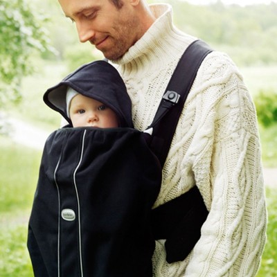 Homem com canguru preto a transportar bebé com capuz ao ar livre