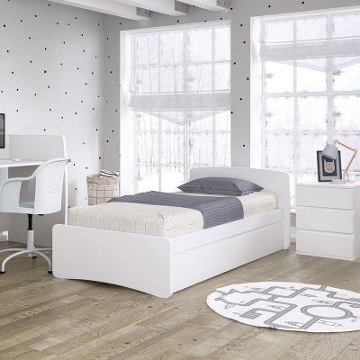 Quarto individual com cama branca, secretária, cómoda, candeeiro, cadeira e tapete sobre chão em madeira clara