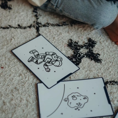Cartas ilustradas de astronauta e asteróide sobre tapete com criança ao lado