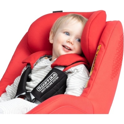 Criança num assento de carro vermelho com arnês preto e texto visível