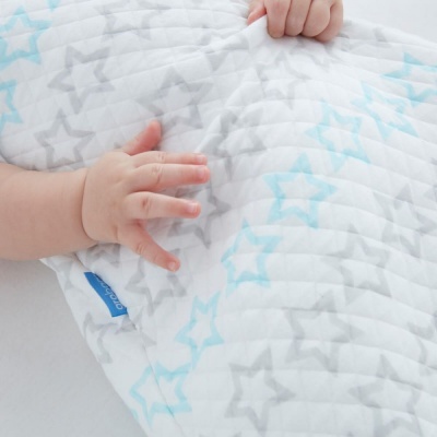 Bebé a tocar tecido acolchoado branco com estampado de estrelas azuis e cinzentas