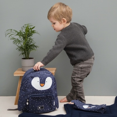 Mochila infantil azul escura com rosto de pinguim e menino ao lado