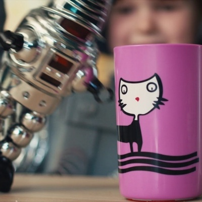 Copo rosa com desenho de gato branco e preto sobre mesa de madeira