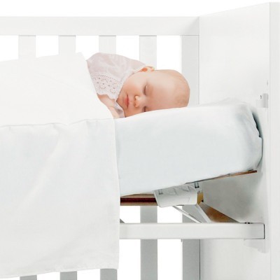 Bebé a dormir em berço branco com lençol branco