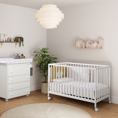 Quarto de bebé com berço e cómoda brancos, plantas e decoração minimalista.