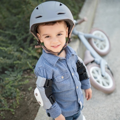 Criança com capacete e equipamento de proteção ao lado de bicicleta infantil