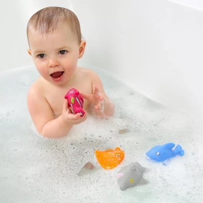 Bebé na banheira com brinquedos de animais coloridos