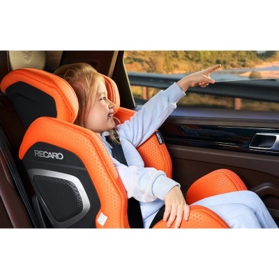 Cadeira auto Recaro laranja para criança dentro de carro com interior castanho