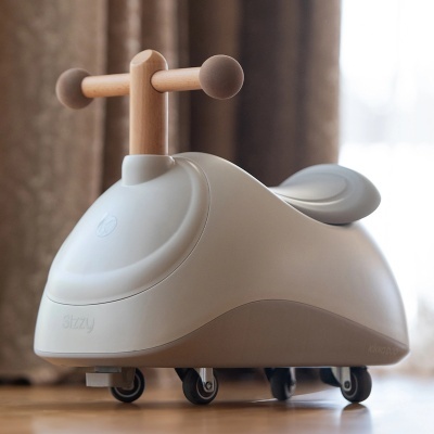 Carrinho de passeio infantil bege com estrutura de madeira e quatro rodas em chão de madeira