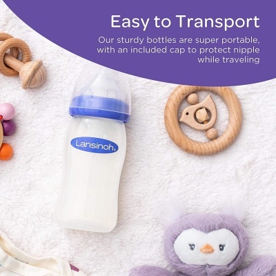 Mamadeira Lansinoh com tampa azul e brinquedos infantis sobre tecido branco