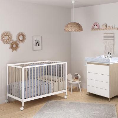 Quarto infantil com berço branco, cómoda com trocador, cadeira pequena e decoração em ráfia e madeira clara