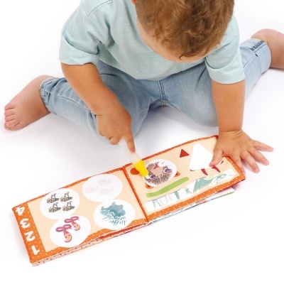 Criança a brincar com livro de tecido colorido sentado no chão branco