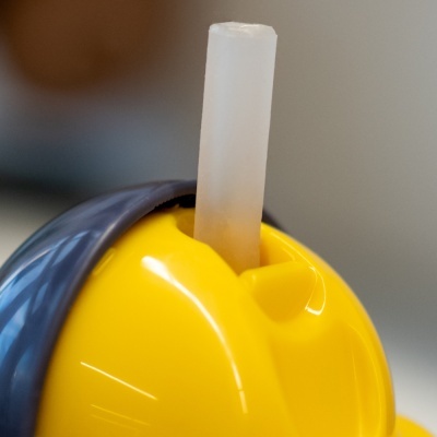 Tampa amarela de plástico com canudo translúcido em recipiente azul