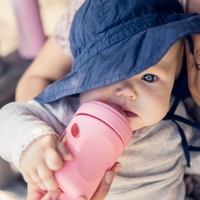 Criança com chapéu azul bebe de copo rosa Tommee Tippee