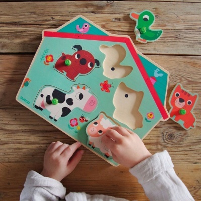 Puzzle de madeira com peças de animais da quinta e mãos de criança