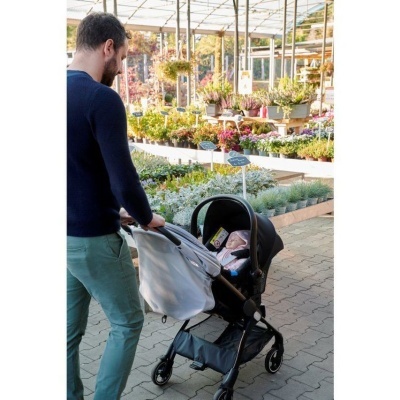 Homem empurra carrinho com bebé numa estufa de plantas