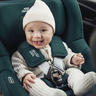 Bebé sentado numa cadeira auto verde escuro com tiras de segurança acolchoadas.