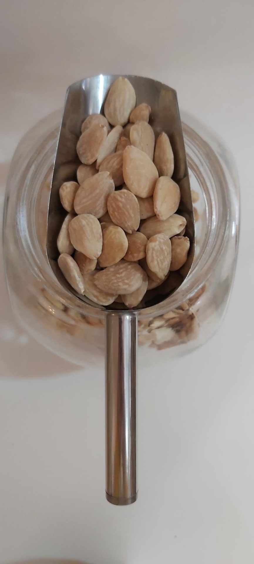 Amêndoa Torrada Sem Pele GRANEL Colher metálica com amêndoas acima de frasco de vidro
