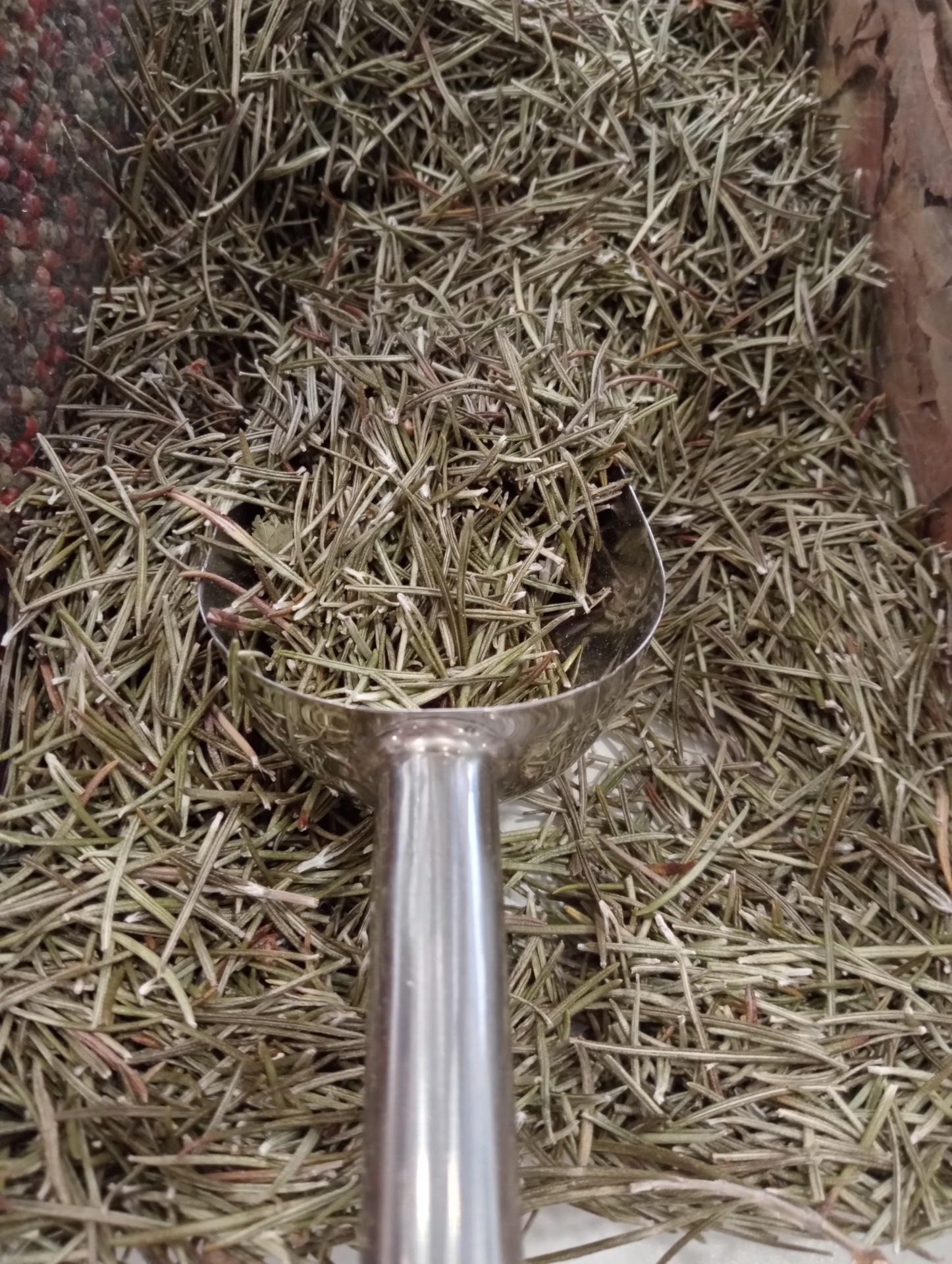 Alecrim Seco GRANEL Colher metálica sobre cascas secas castanho-acinzentadas em recipiente de madeira