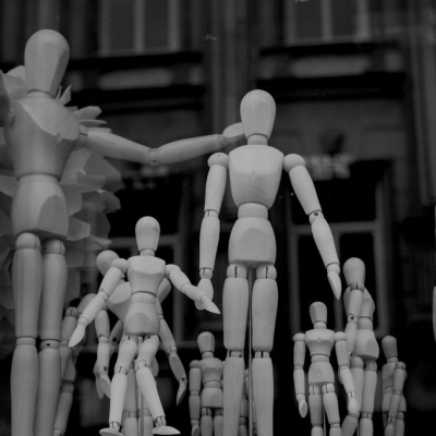 Figuras humanas articuladas de madeira em vários tamanhos, dispostas como multidão