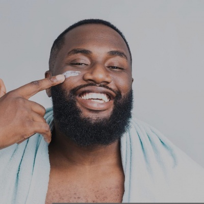 Homem a aplicar creme facial com toalha azul ao ombro