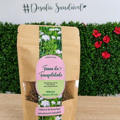 Pacote de tisana da tranquilidade com rótulo rosa e verde sobre mesa de madeira e fundo com plantas e texto na parede