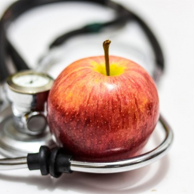 Maçã vermelha sobre estetoscópio de metal e preto em fundo branco