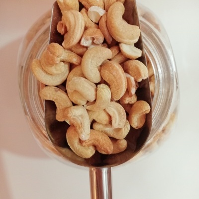 Concha de metal com anacardos crus sobre frasco de vidro transparente