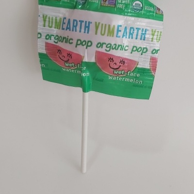 Embalagem verde e branca de pirulito YumEarth com melancia sorridente