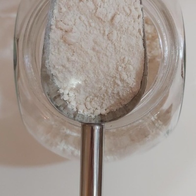 Colher metálica cheia de farinha branca dentro de frasco transparente