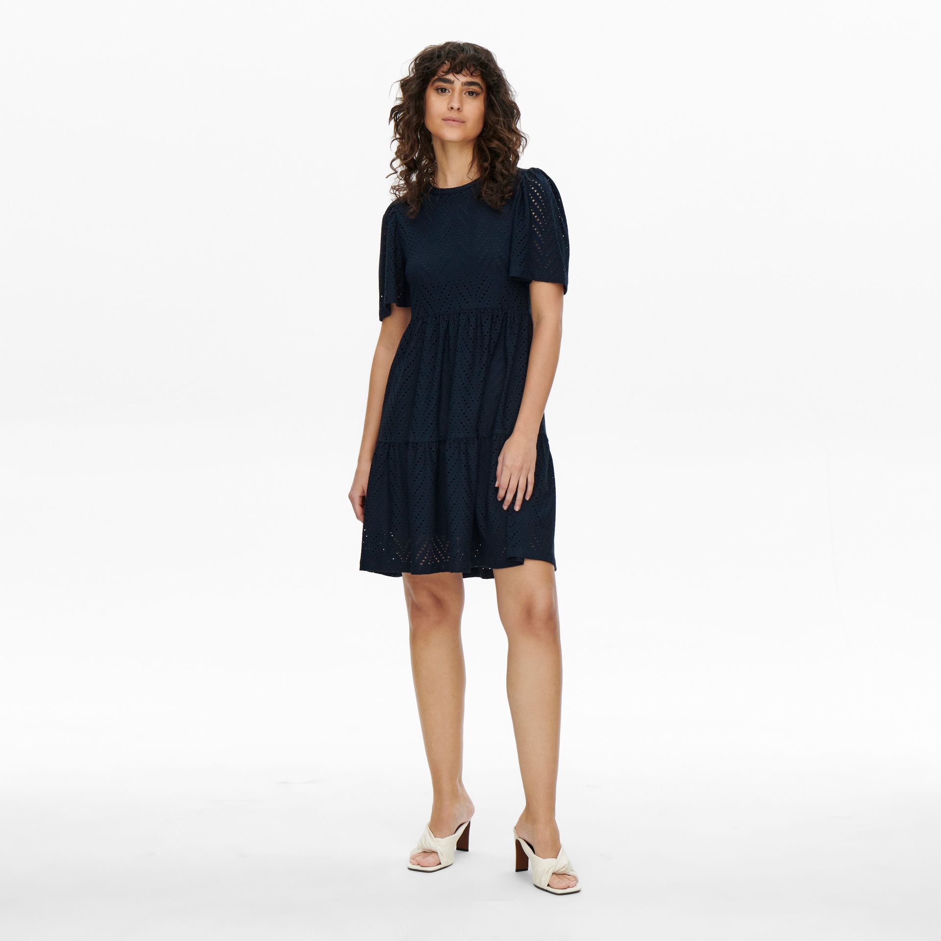 Vestido curto azul escuro com padrão de pequenos furos e mangas curtas podem ser vistas numa modelo em fundo branco