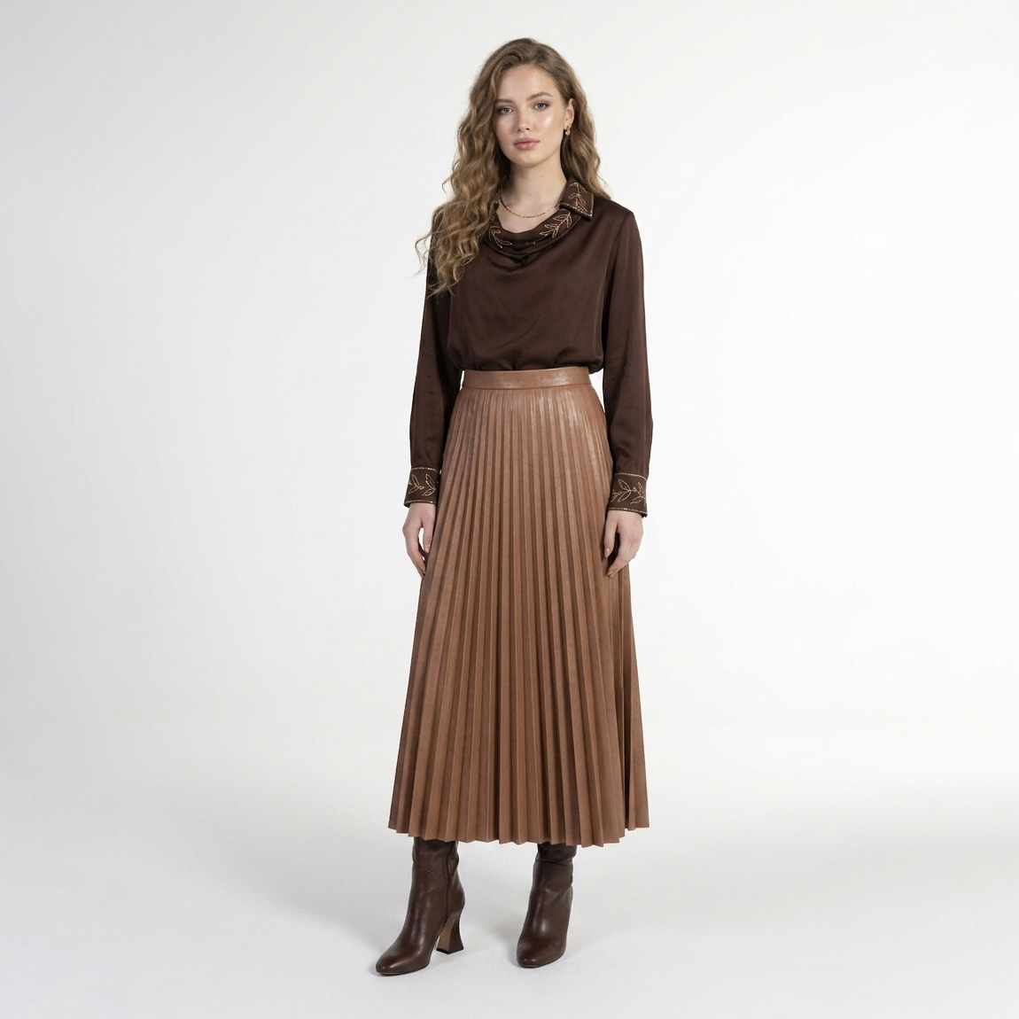Mulher com blusa e saia castanhas e botas, em fundo branco
