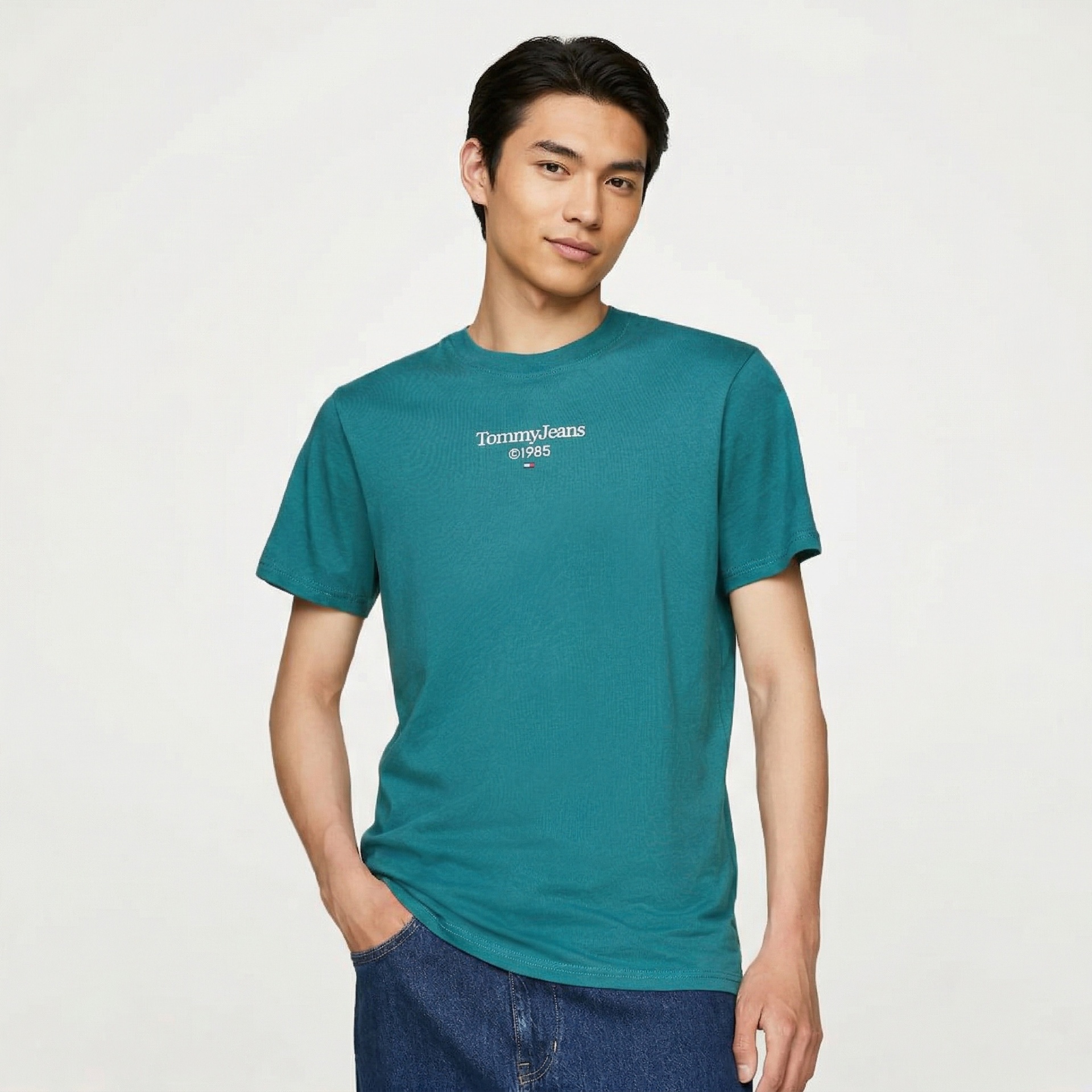 T-shirt azul-turquesa Tommy Jeans com texto branco e modelo com calças de ganga azuis