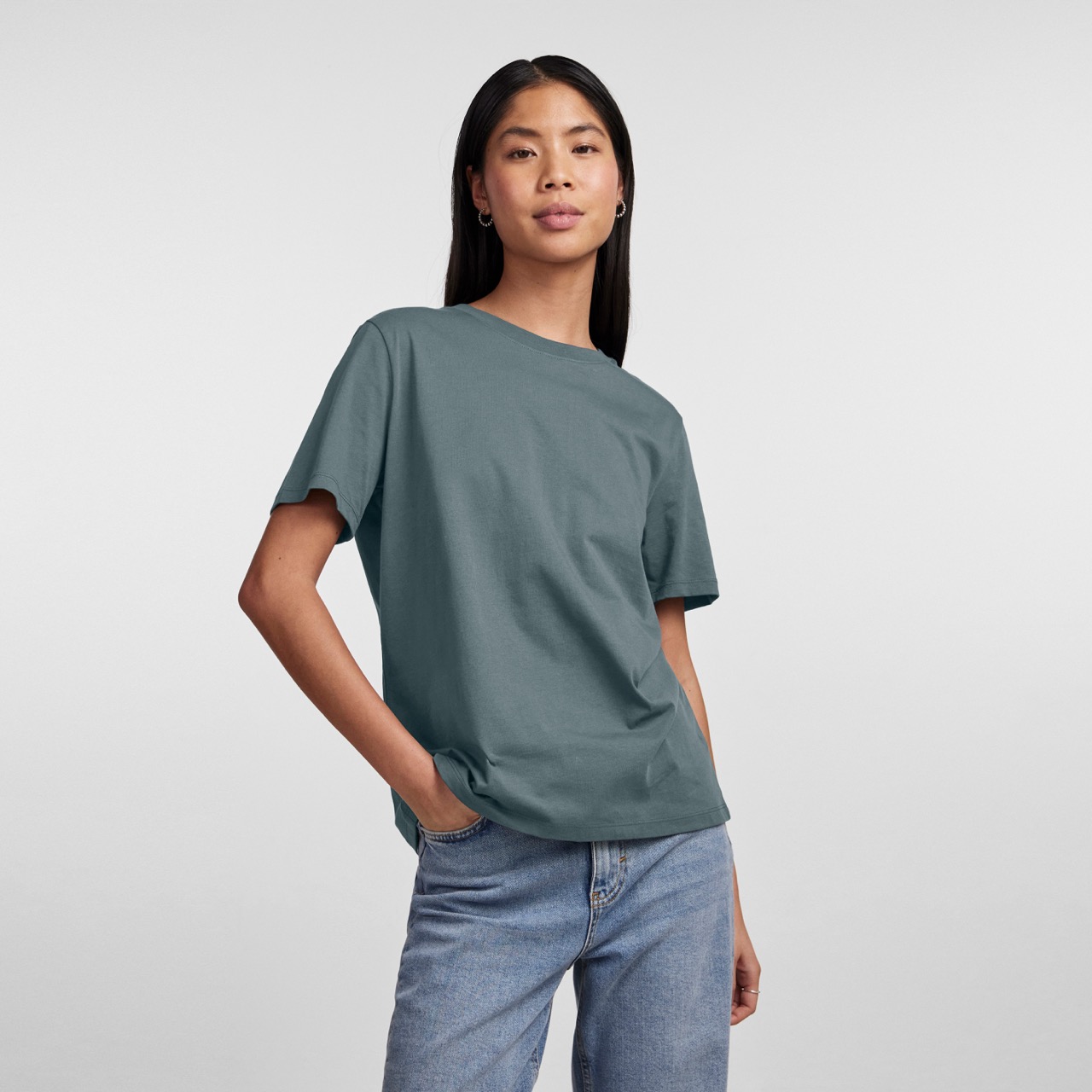 Camiseta cinzento azulado de manga curta vestida com calças de ganga azuis claras.