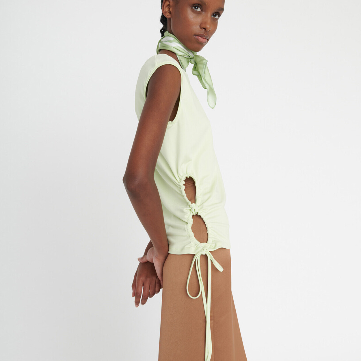 Camisa verde clara sem mangas com recortes e calças castanhas