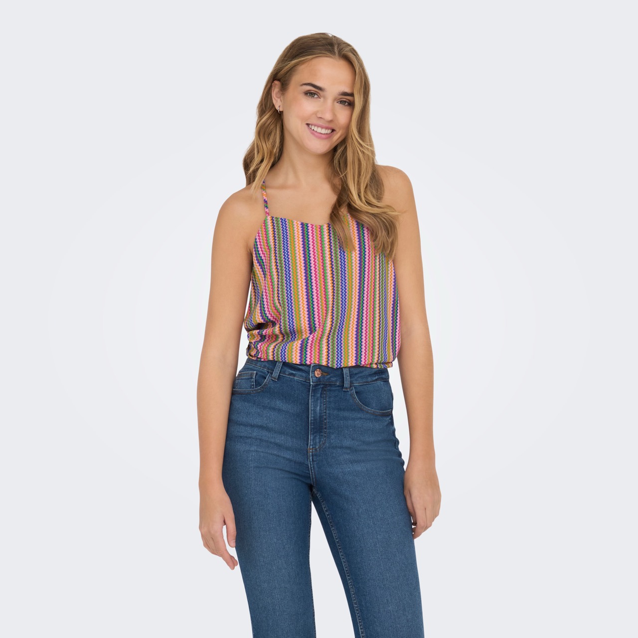 mulher com top de riscas coloridas e jeans azul escuro