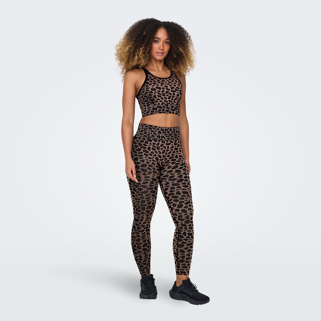 Conjunto desportivo feminino padrão animal print castanho e preto com top e leggings.