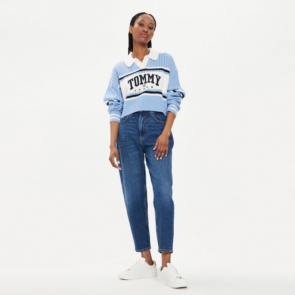 Mulher com camisola azul TOMMY JEANS, calças de ganga e ténis brancos
