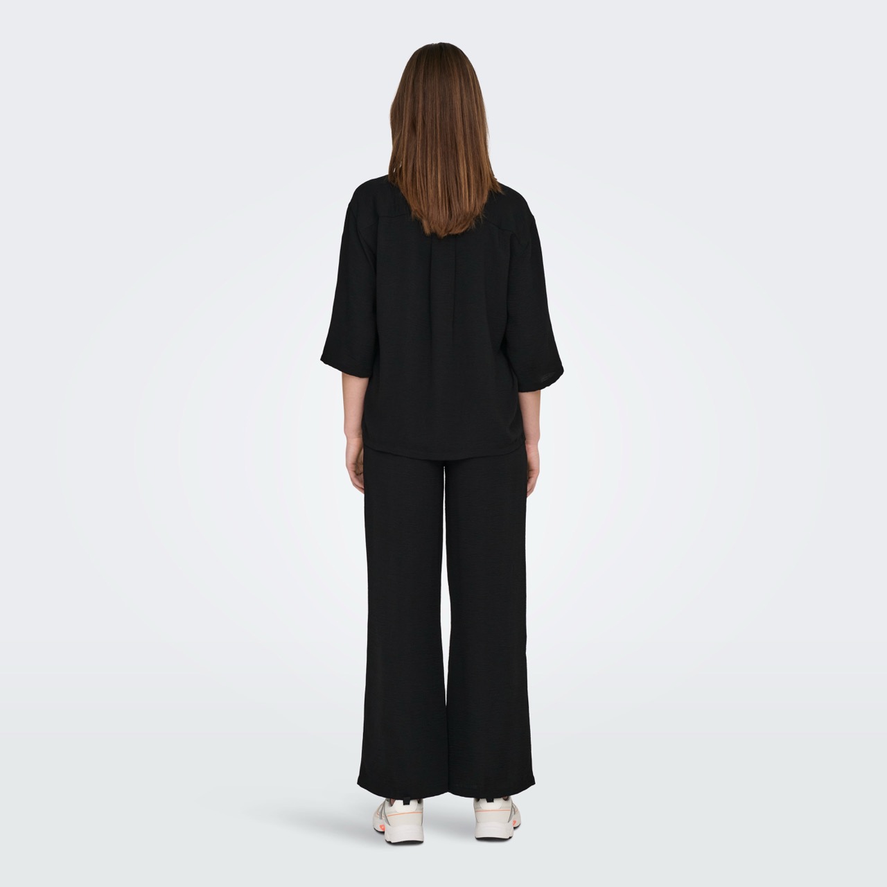 Conjunto preto de blusa e calças largas visto de costas
