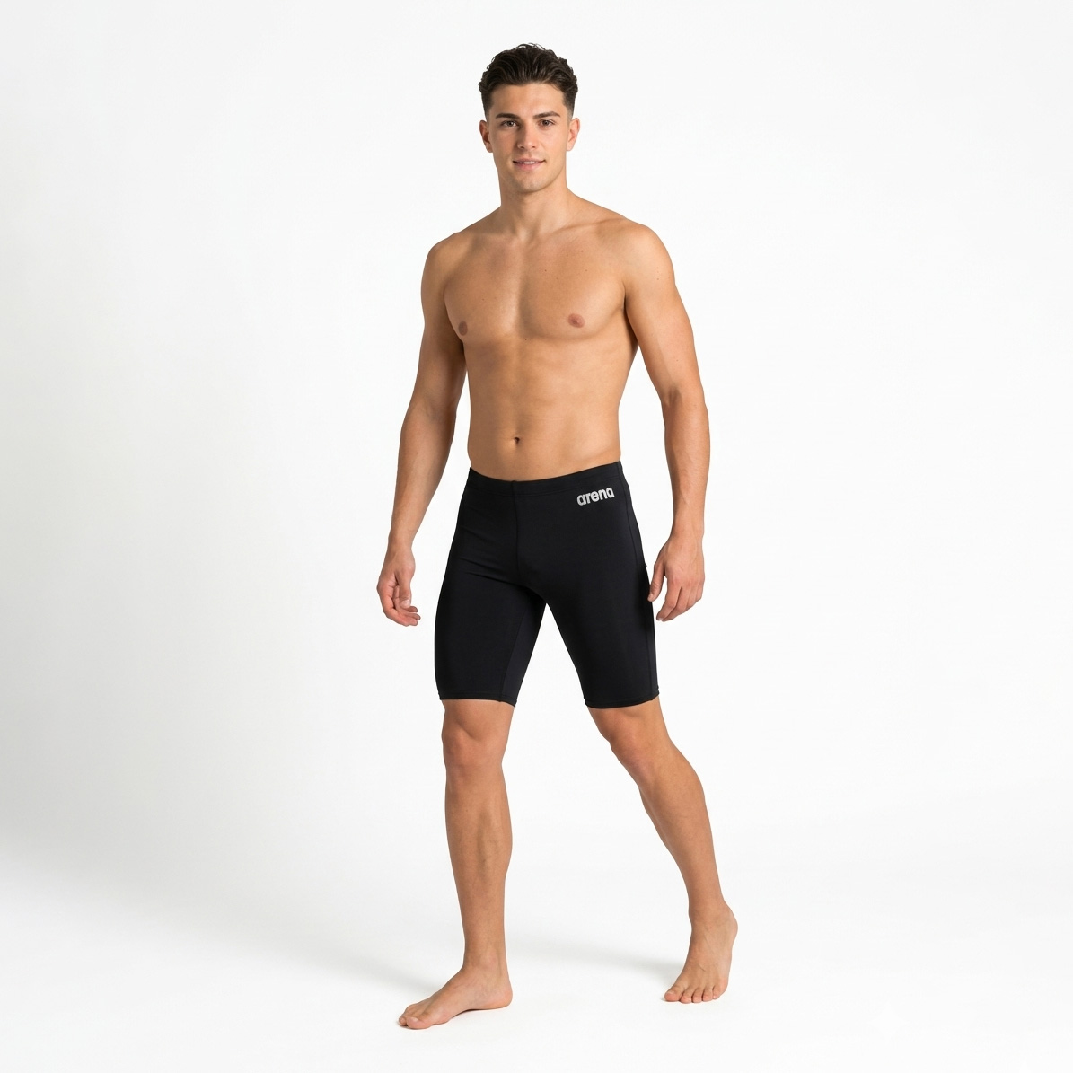 Homem jovem de pé com calções de banho pretos com logótipo branco arena