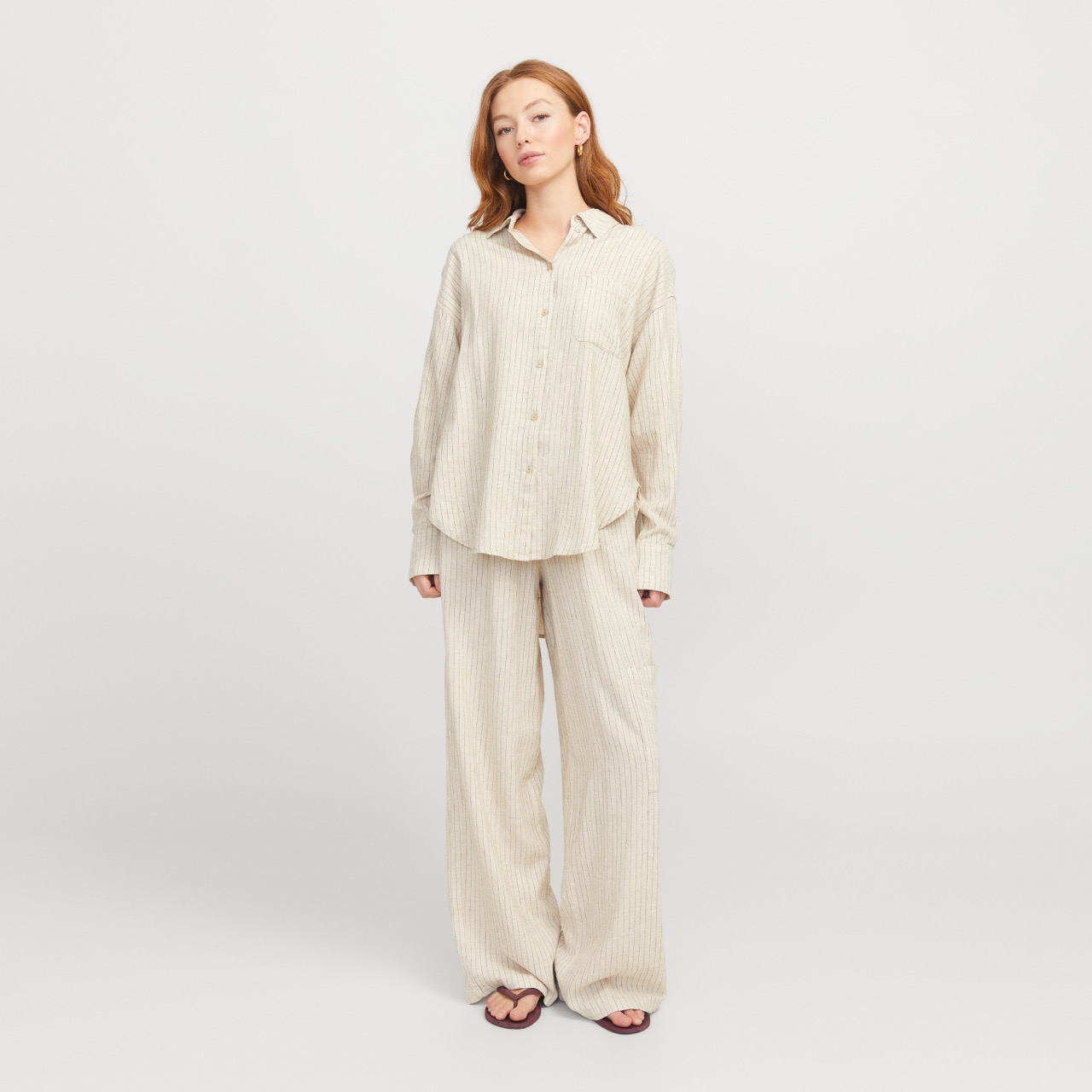 Conjunto de pijama bege de riscas finas de mulher em fundo branco