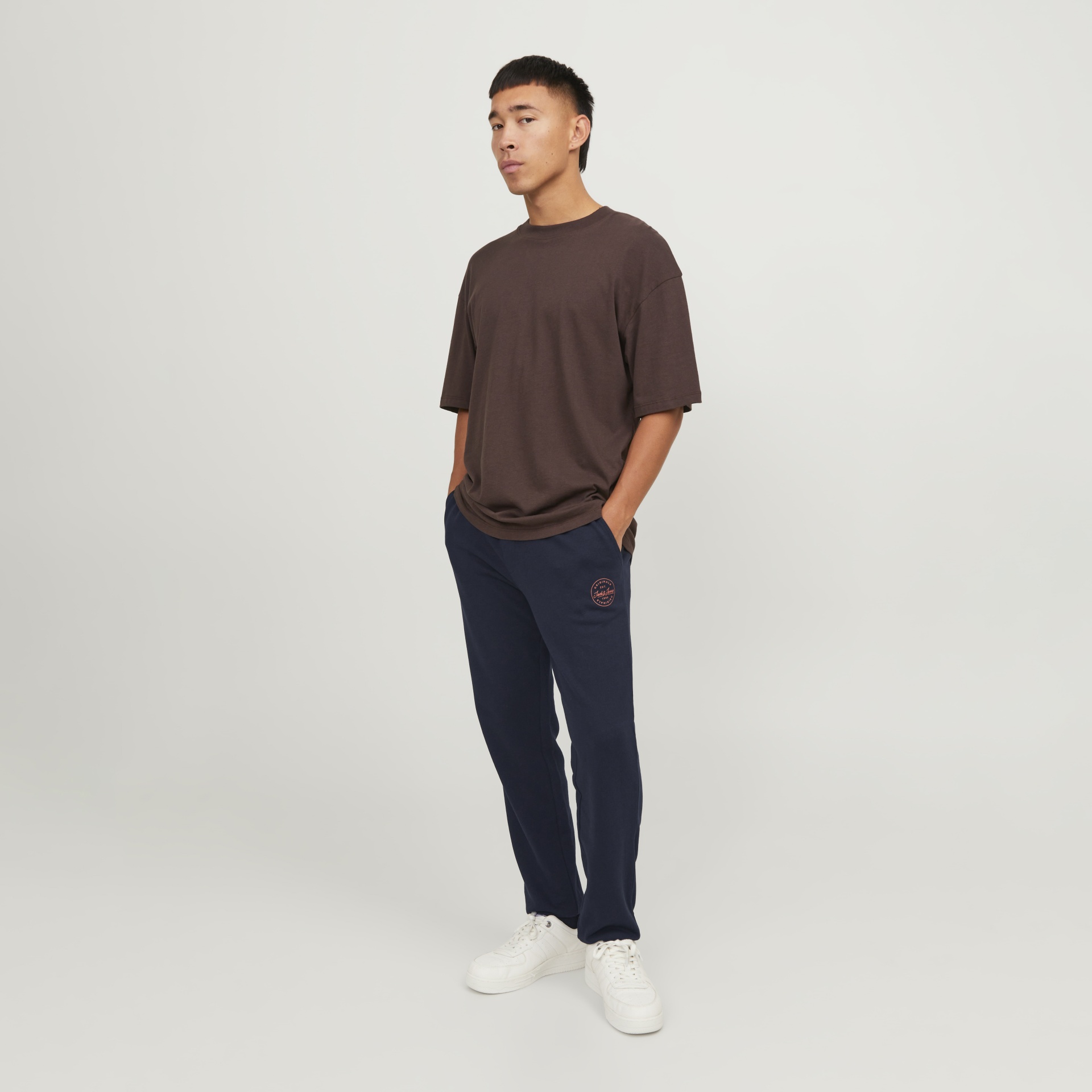 Homem com roupa casual castanha e azul-marinho e ténis brancos